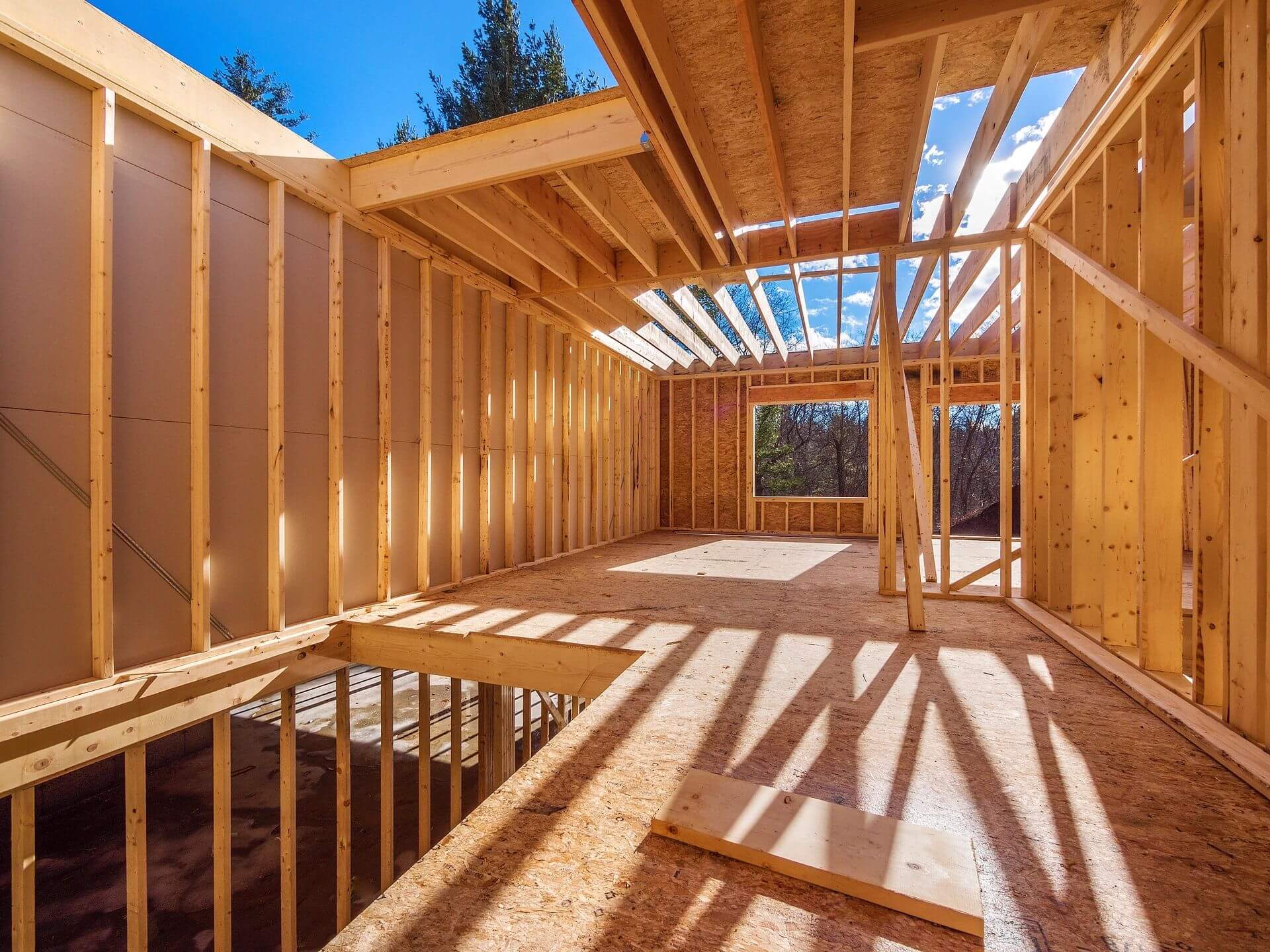 A wooden house being built with the sun shining.